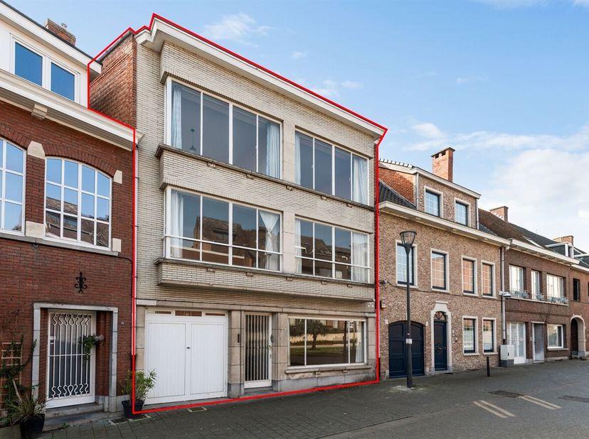 Ruime gezinswoning met 7 slaapkamers en zuidgerichte stadstuin<br />
Gelijkvloers<br />
Via de inkomhal met gastentoilet betreedt u de woning. De ruim