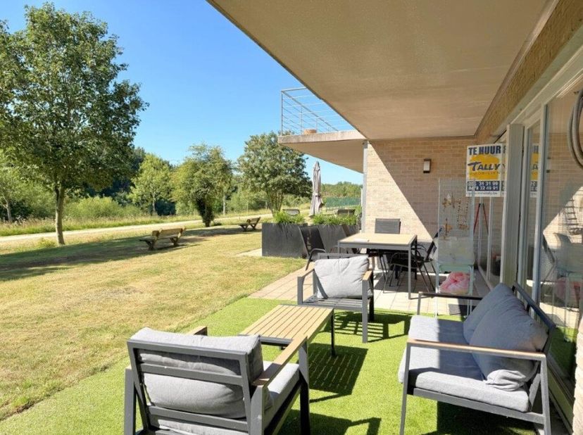 Prachtig gelegen gelijkvloers appartement met inkomhal, apart toilet, ruime living, volledig uitgeruste keuken, badkamer, 2 slaapkamers, berging en ee