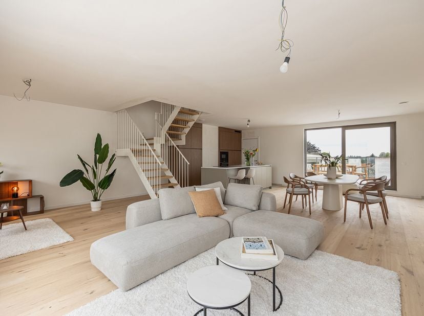 Via de inkom met apart toilet en berging bereikt men de riante leefruimte (66 m²) op parketvloer met open keuken en terras aan de voor- en achterzijde