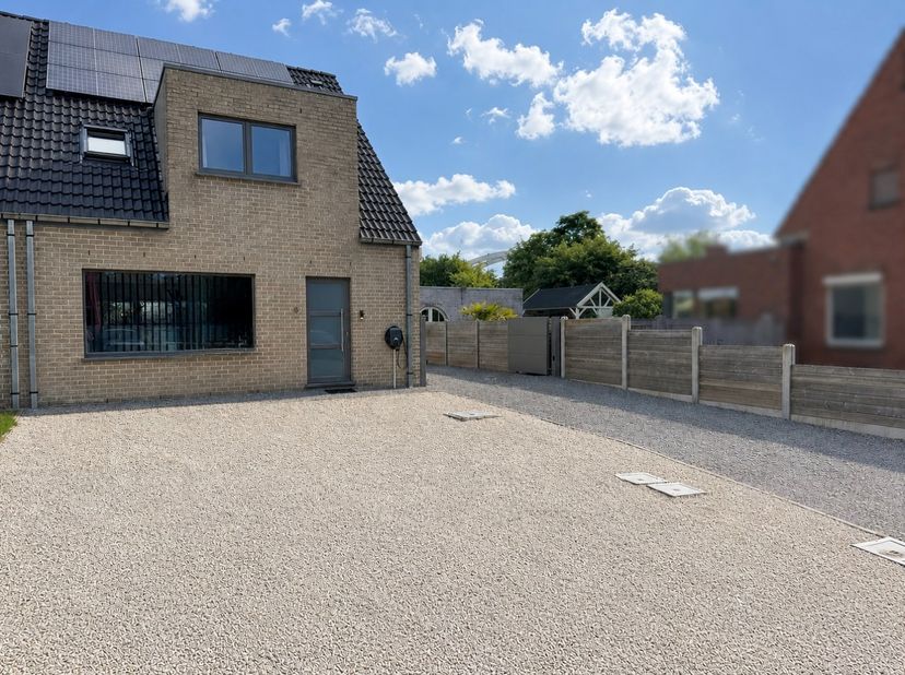 We komen de woning binnen in de lichtrijke inkomhall met gastentoilet. De ruime living heeft zicht op de tuin en sluit aan bij de half-open volledig i