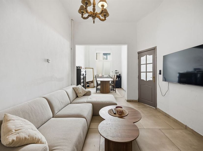 De statige voorgevel van deze hoge woning met dito plafonds, werd voorzien van een mooie plint in blauwe hardsteen en witte sierpleister, die goed con