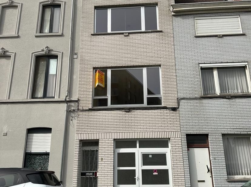 Welgelegen belétage-rijwoning met drie slaapkamers. Op het gelijkvloers bevindt zich een garage en inkomhall met trap naar de verdieping alwaar leefru