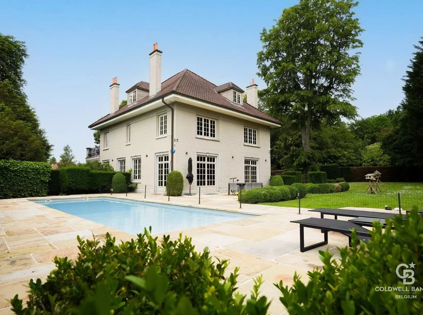 En retrait de la rue, sur un magnifique terrain arboré avec piscine extérieure, cette élégante propriété classique entièrement rénovée offre un cadre