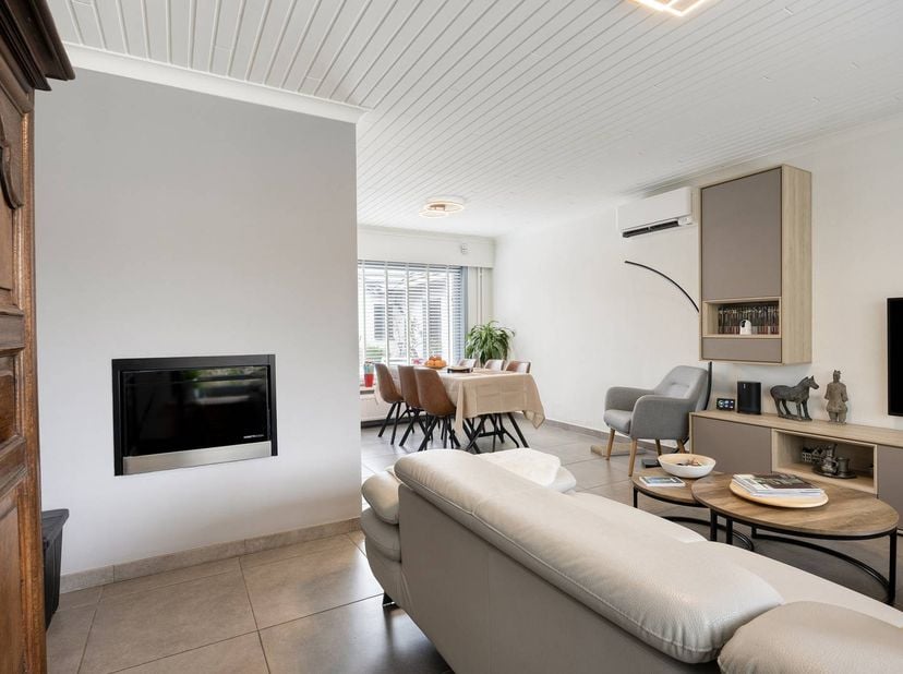 De indeling:<br />
<br />
- Een uitnodigende inkomhal met vestiaire en een modern gastentoilet.<br />
- De lichtrijke woonkamer ademt sfeer en warmte,
