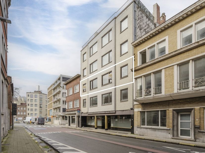 In het hart van Kortrijk, pal in het centrum en op slechts enkele meters van de Grote Markt, bevindt zich dit uitzonderlijk ruime appartement met een