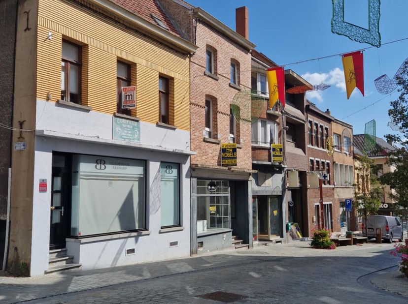 Située dans la rue commerçante à Lessines, maison 3 façades avec beau commerce au rez de chaussée. A l'étage, appartement avec 2 chambres, living, cui