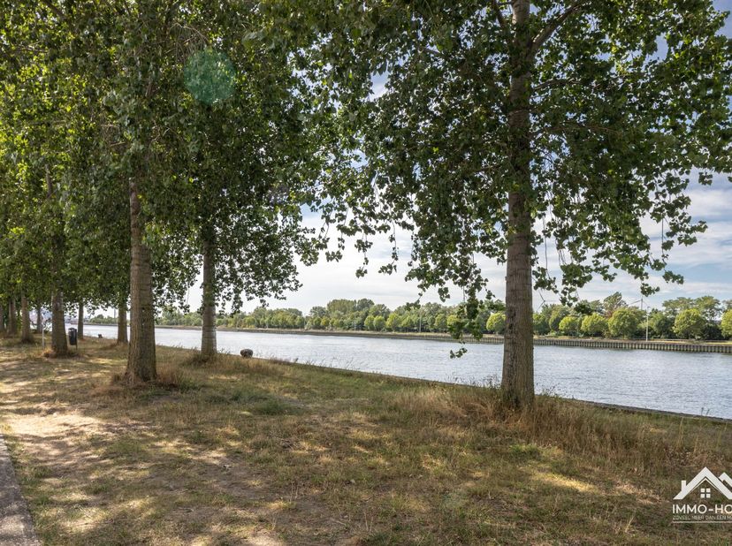 Deze halfopen bebouwing geniet van een bijzonder aantrekkelijke ligging langs het kanaal in Zelzate, met aan de overzijde een sfeervolle bomenrij die