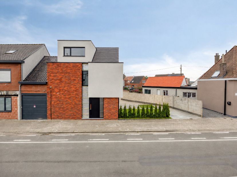 Deze woning onderscheidt zich moeiteloos in het straatbeeld. De combinatie van verfijnde gevelsteen, strakke witte crepi en zwarte platte dakpannen zo