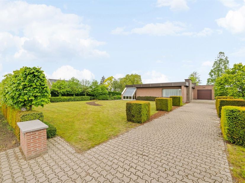 Op een ruim perceel van maar liefst 2385m² treffen we deze alleenstaande bungalow anno 1975 aan, gelegen op een steenworp van het centrum de 'Madone'