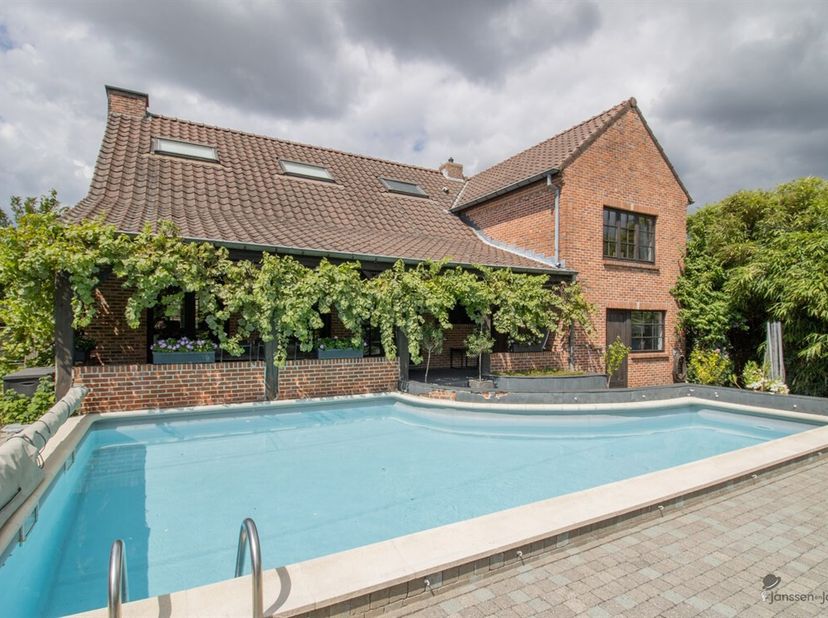 Ruime woning met min. 3 slaapkamers, polyvalente zolderruimte van 60 m² en zwembad.  <br />
Gelijkvloers: <br />
Inkomhal met apart toilet. <br />
Woo