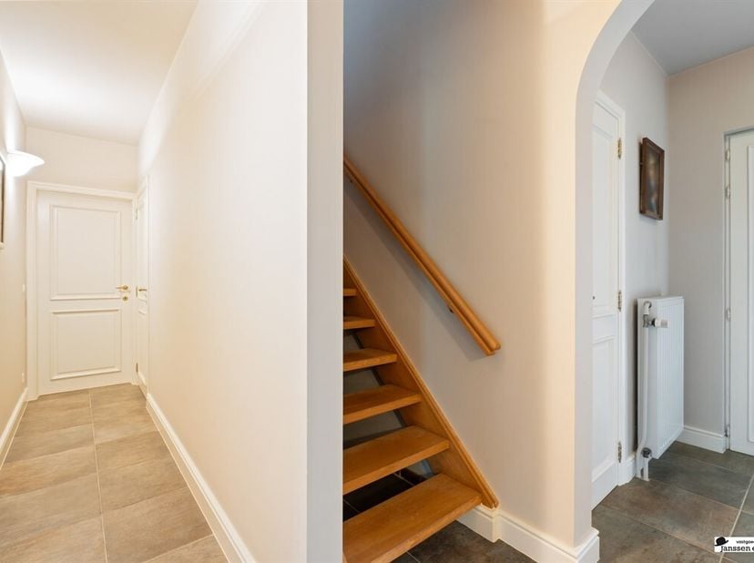 Située au centre, cette villa spacieuse offre un espace de vie lumineux avec une cheminée à gaz et de grandes fenêtres donnant sur le jardin. La cuisi