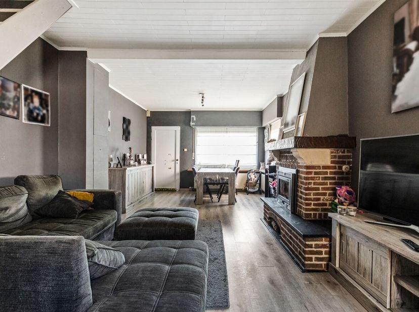 Half open bebouwing met 3 slaapkamer en zonnige tuin.<br />
We betreden de woonkamer. Deze geniet van een houtkachel en is ruim genoeg om eetplaats en