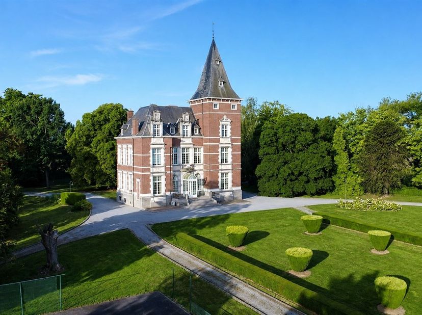 Het kasteel:<br />
De statige toegangspoort en lange oprijlaan leiden naar het kasteel, gebouwd in 1904-1907 in eclectische stijl. In 1988 werd het k