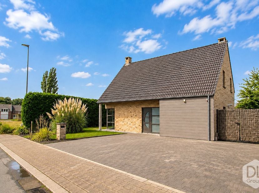 Op het gelijkvloers, leidt de inkomhal naar een apart toilet en een ruime L-vormige leefruimte met houtinbouwhaard. De ingerichte keuken sluit aan op