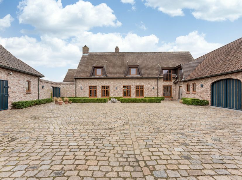 Te midden van het groene en glooiende landschap van Oosterzele bevindt zich deze uitzonderlijke vierkantshoeve met binnenkoer, paardenfaciliteiten en