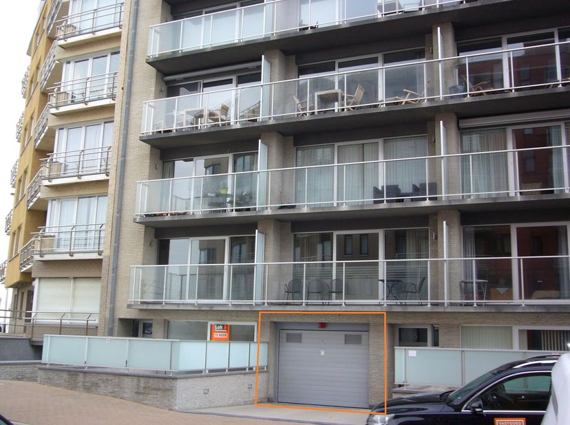 Autostaanplaats nummer 12 in de parking van residentie Virgo,  het hoekgebouw op de Westlaan met de Zeedijk in Raversijde-Bad.<br />
De autostaanplaat