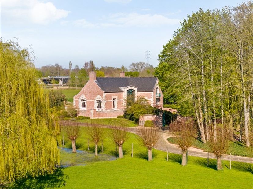 Via een lange oprit in authentieke kinderkopjes bereikt u deze indrukwekkende eigendom, gelegen op een uitzonderlijk perceel van 7.542 m². Discreet ge
