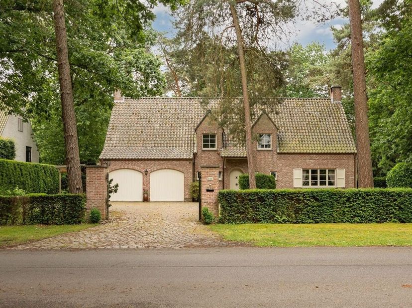 Klassieke villa op 2.233m² met zuid-georiënteerde tuin.  Gelijkvloers : inkomhal op lichte natuursteen met gastentoilet, ruime living in L-vorm op pra