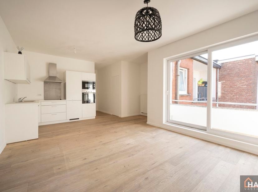 Inkomhal; leefruimte met open, geïnstalleerde keuken en schuifraam naar terras; 2 slaapkamers; badkamer met douche, toilet, lavabo in meubel en spiege