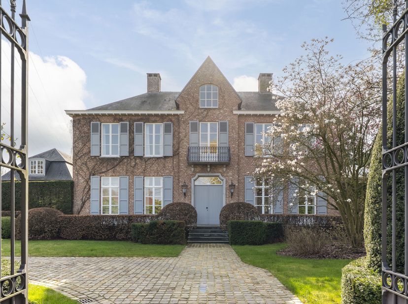 Nichée dans un écrin de verdure et entourée d'une grande variété d'arbres, d'arbustes rares et de haies soigneusement taillées, cette villa de caractè