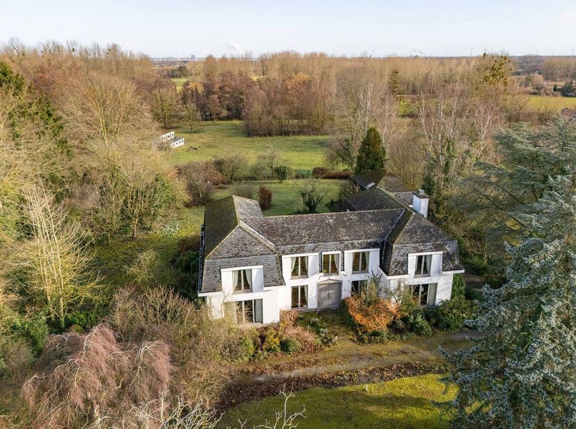 Deze karaktervolle kasteelvilla, ontworpen door architect C. Bogaerts en gebouwd in 1976, is gelegen op een uitzonderlijk groen en discreet domein in