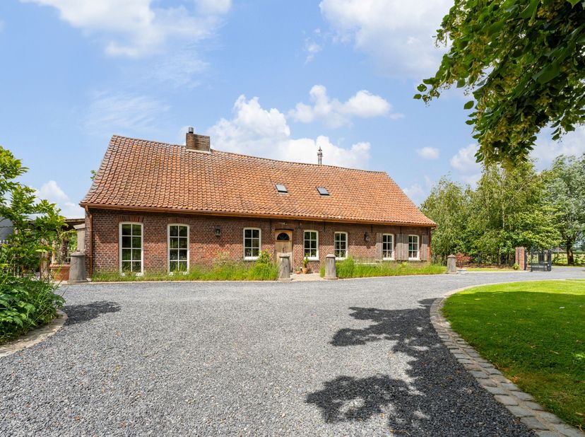 Via een lange oprijlaan, omgeven door groen en velden, bereik je deze prachtig gelegen hoeve in het landelijke Sint-Eloois-Winkel. Op een perceel van