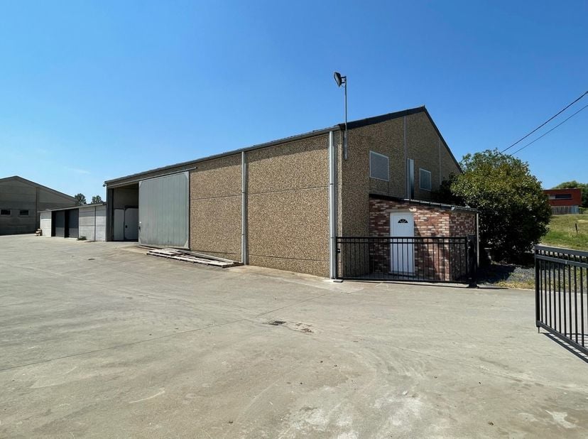 Aan de rand van het dorp, grote, vrijstaande loods van ongeveer 317 m² (15,40 m Ã 20,60 m) met een gladde betonnen vloer. Mooie hoogte en grote schuif