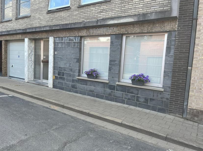 Dit appartement (95m2) is op het gelijkvloers gelegen en omvat een private inkom met toilet, ruime woonkamer met open keuken, twee slaapkamers (waarva