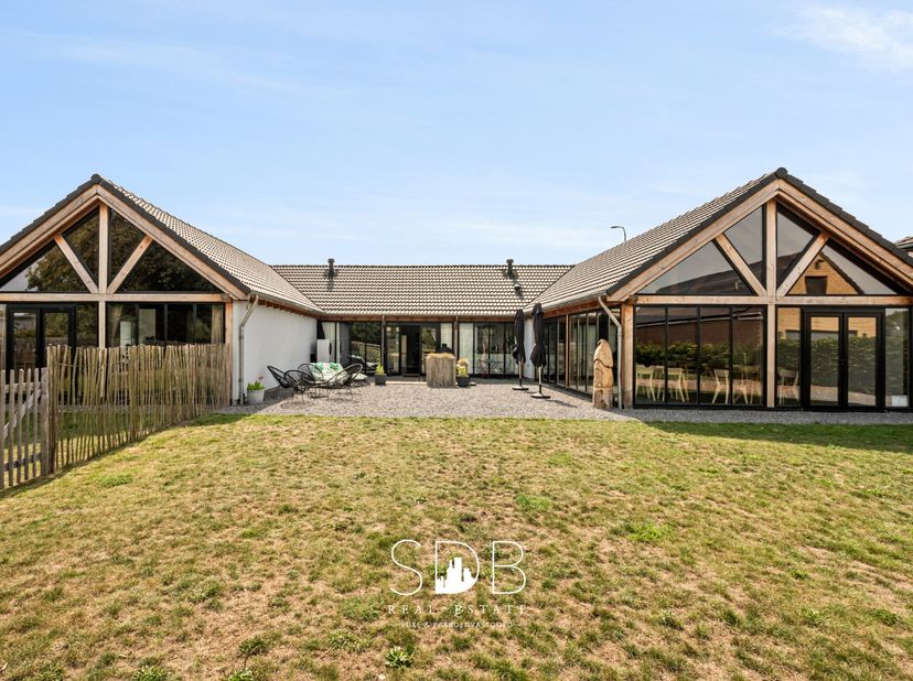 In Wachtebeke, een deelgemeente van Lochristi, bevindt zich deze uitzonderlijke hedendaagse woning met wijngaard en graslanden op een perceel van maar