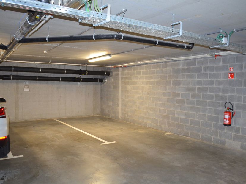 Emplacement de parking au sous-sol de la Résidence Guimard à Nivelles. Accès facile, ouverture automatique avec télécommande, emplacement équipé d'un