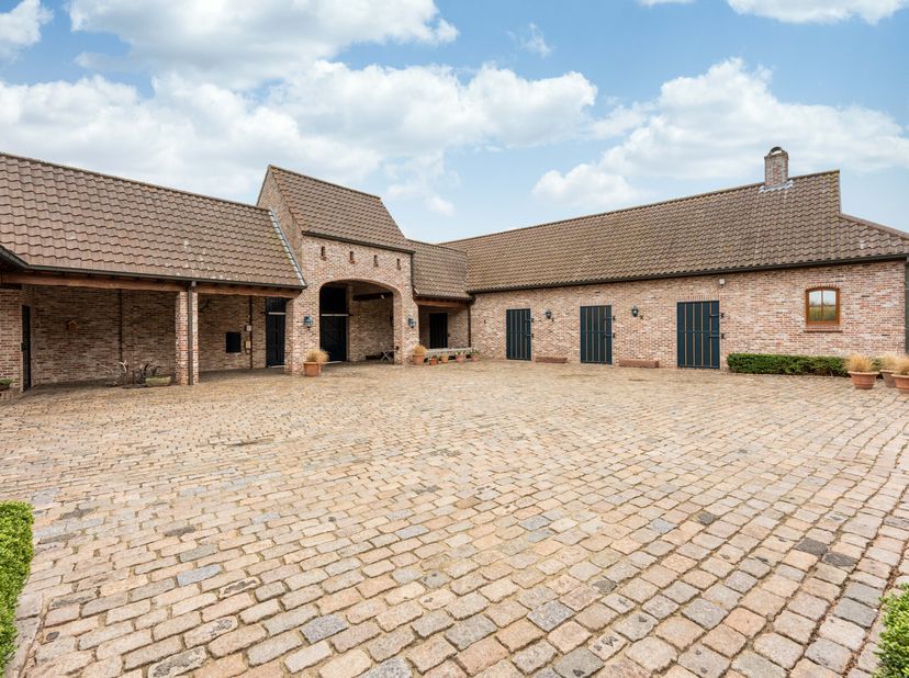 Au cur du paysage verdoyant et vallonné d'Oosterzele se trouve cette exceptionnelle ferme carrée avec cour intérieure, installations pour chevaux et p