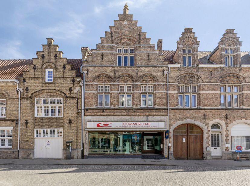 Handelswoning met prachtige gevel op 50m van de Grote Markt van Ieper. Commercieel gelijkvloers van +/- 200m² met mooie grote open ruimte. Achterligge