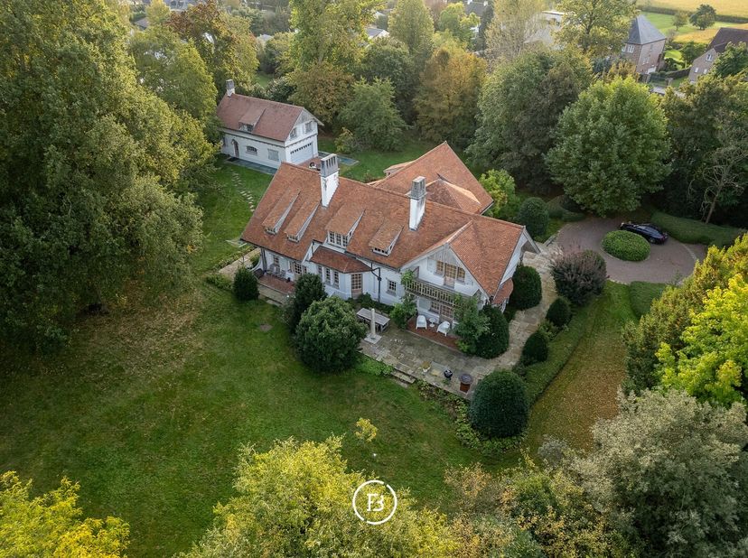 Gelegen op een prachtig perceel van 5.630 m² in een doodlopende straat, binnen een residentieel kader, presenteren we u dit landhuis met bijhuis in co