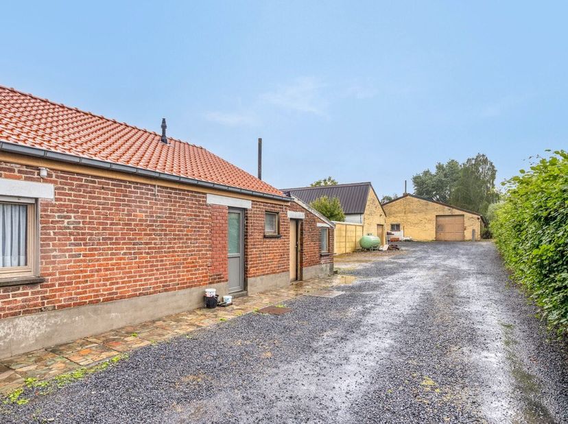 Een oprit naast de woning vergemakkelijkt de toegang om met een vrachtwagen de werkplaatsen te bereiken. Een werkplaats van 75m2 en een werkplaats van