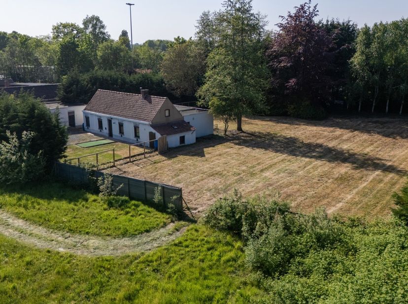 Nabij de Karmel te Waregem, ligt deze te renoveren woning met ruim bijgebouw op royaal perceel grond op het einde van een doodlopende straat. Privacy