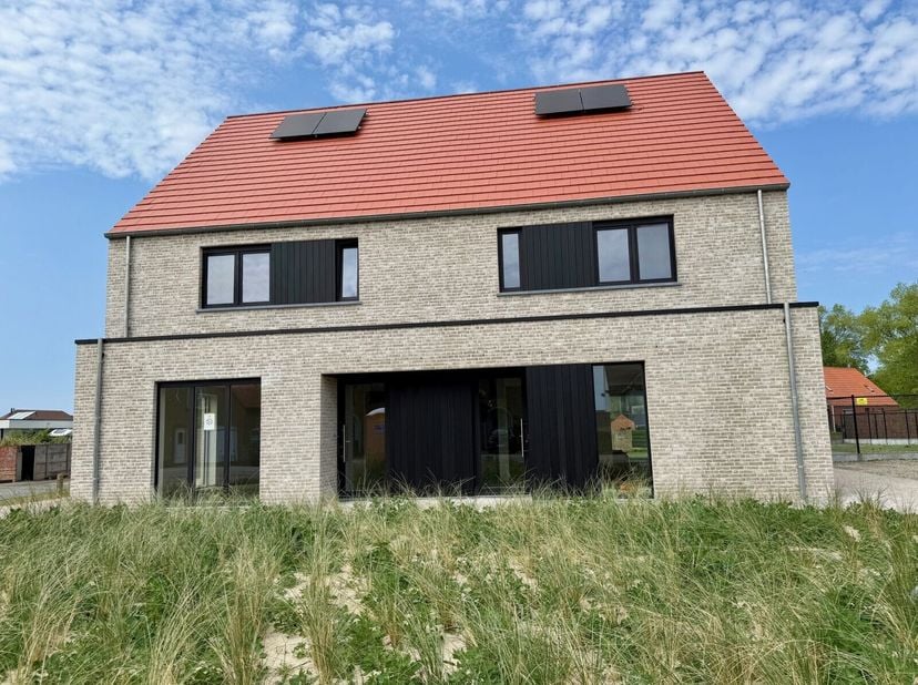 Half-open nieuwbouw met op het gelijkvloers een inkomhal met gastentoilet, ruime eet- en zithoek, open ingerichte keuken met zicht op de tuin en aansl