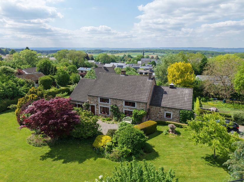 Nichée sur les hauteurs de Wéris, dans un cadre verdoyant, cette magnifique maison en pierre du pays séduit par son authenticité et la qualité de ses