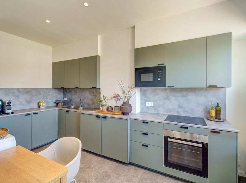 Gelegen aan de Mechelsesteenweg in Hove, biedt dit gerenoveerd duplex appartement van meer dan 100m2 boven een toekomstig vastgoedkantoor een comforta