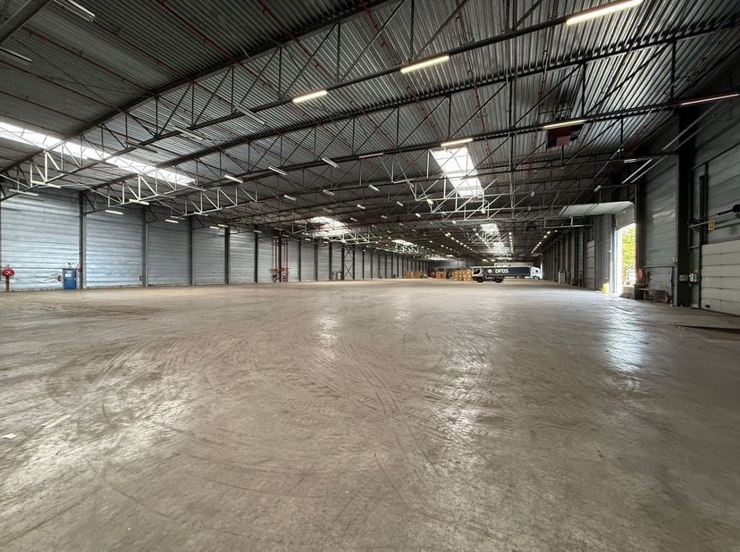 Deze ruime opslagruimte met een oppervlakte van 8830 m² beschikt over een vrije hoogte van 8 meter en is uitgerust met 3 automatische sectionale poort