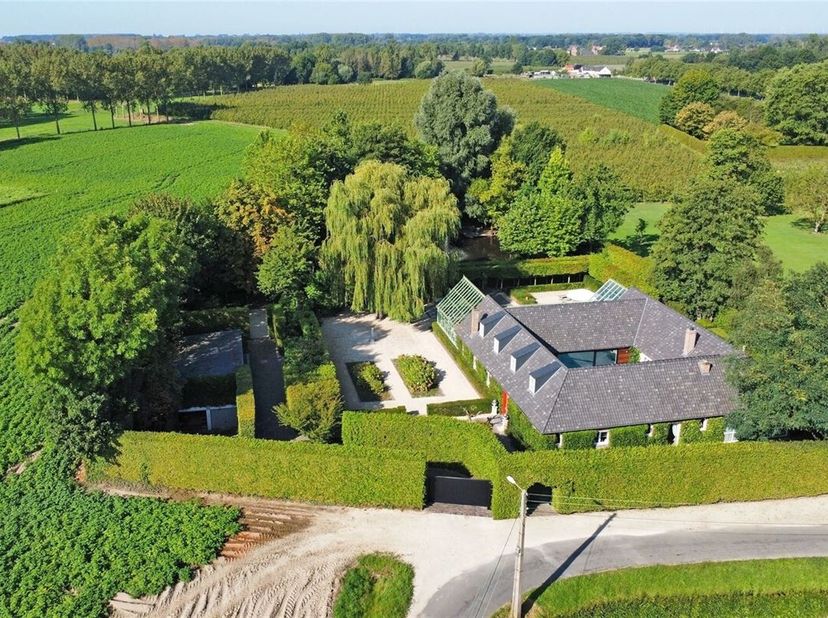 Achter een afgesloten toegangspoort met prachtig aangelegde binnenkoer bevindt zich deze charmante vierkantshoeve, welke door de jaren heen een volled