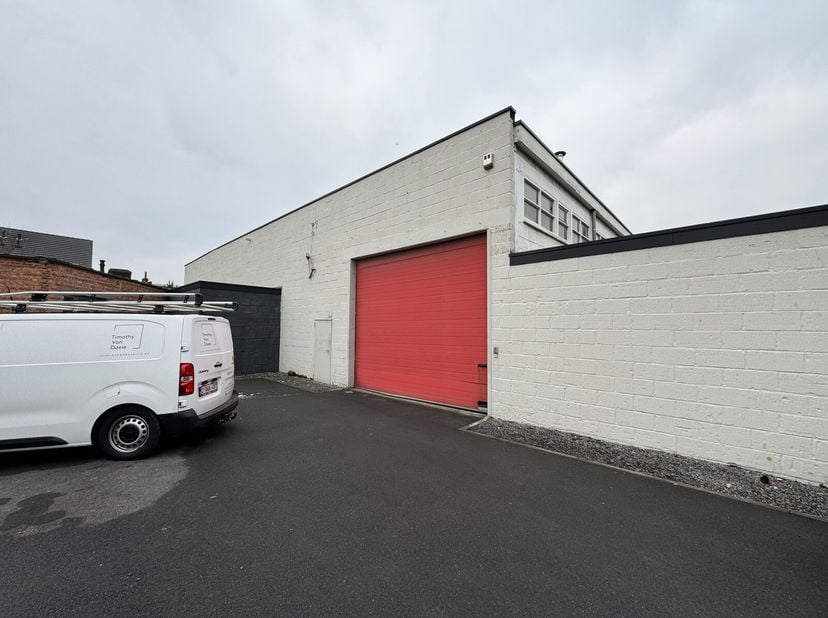 Entrepôt rénové à vendre (1 013 m²) avec une grande porte sectionnelle et mezzanine, situé dans un quartier résidentiel calme à Wilrijk, à proximité d